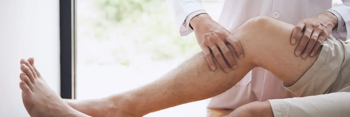 Arzt untersucht das Knie eines Patienten Arzt untersucht das Knie eines Patienten, Fokus auf das Bein und die Hände des Arztes