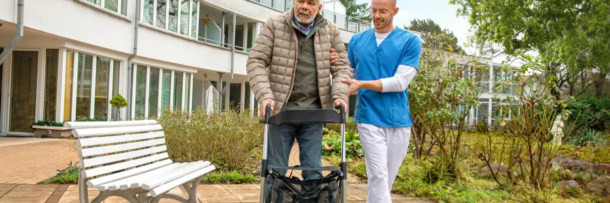 Älterer Mann mit Rollator gestützt von einem Altenpfleger Älterer Mann mit Rollator gestützt von einem Altenpfleger