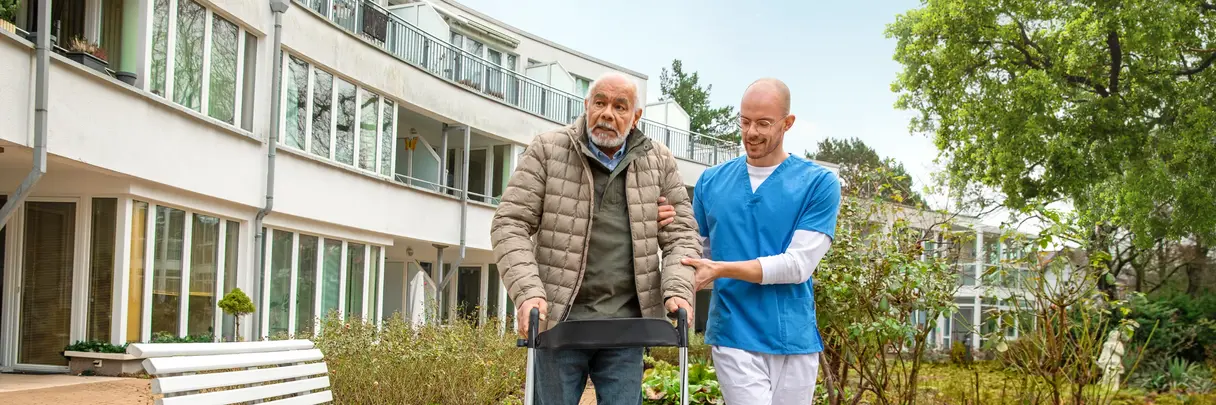 Älterer Mann mit Rollator gestützt von einem Altenpfleger Älterer Mann mit Rollator gestützt von einem Altenpfleger