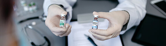 Arzt zeigt zwei verschiedene Coronavirus-Impfstoffe (Symbolbild)