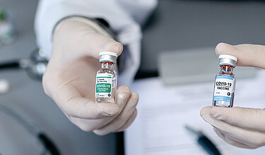 Arzt zeigt zwei verschiedene Coronavirus-Impfstoffe (Symbolbild)