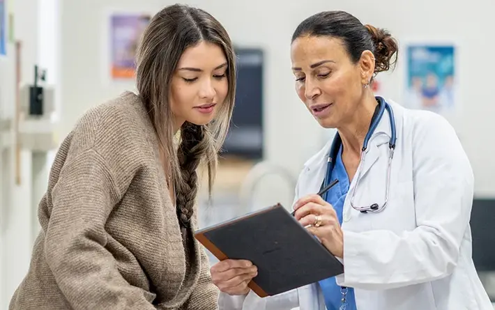 Ärztin erklärt einer Patientin in der Praxis gemeinsam eine Entscheidung anhand eines Tablets