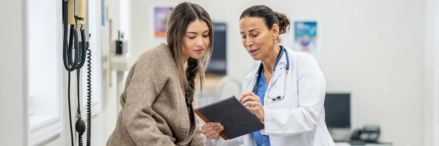 Ärztin erklärt einer Patientin in der Praxis gemeinsam eine Entscheidung anhand eines Tablets