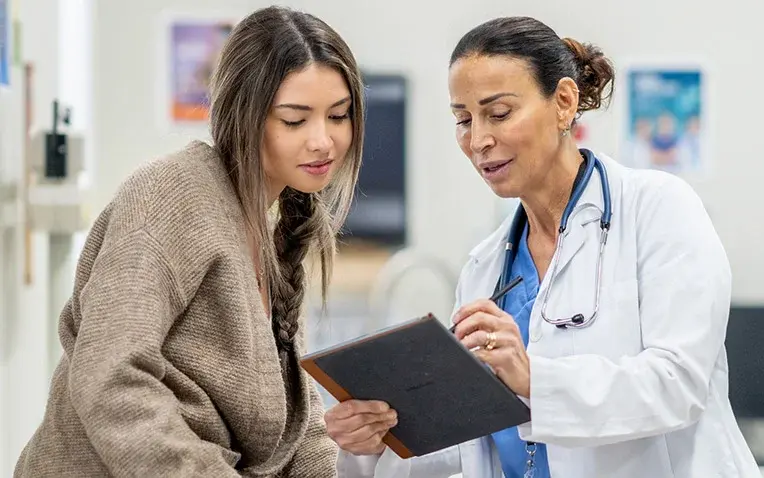 Ärztin erklärt einer Patientin in der Praxis gemeinsam eine Entscheidung anhand eines Tablets