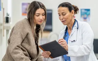 Ärztin erklärt einer Patientin in der Praxis gemeinsam eine Entscheidung anhand eines Tablets