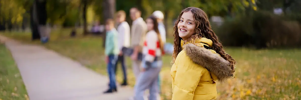 Das Bild zeigt im Vordergrund ein Mädchen im Teenager-Alter, im Hintergrund eine Gruppe von weiteren Mädchen im gleichen Alter.