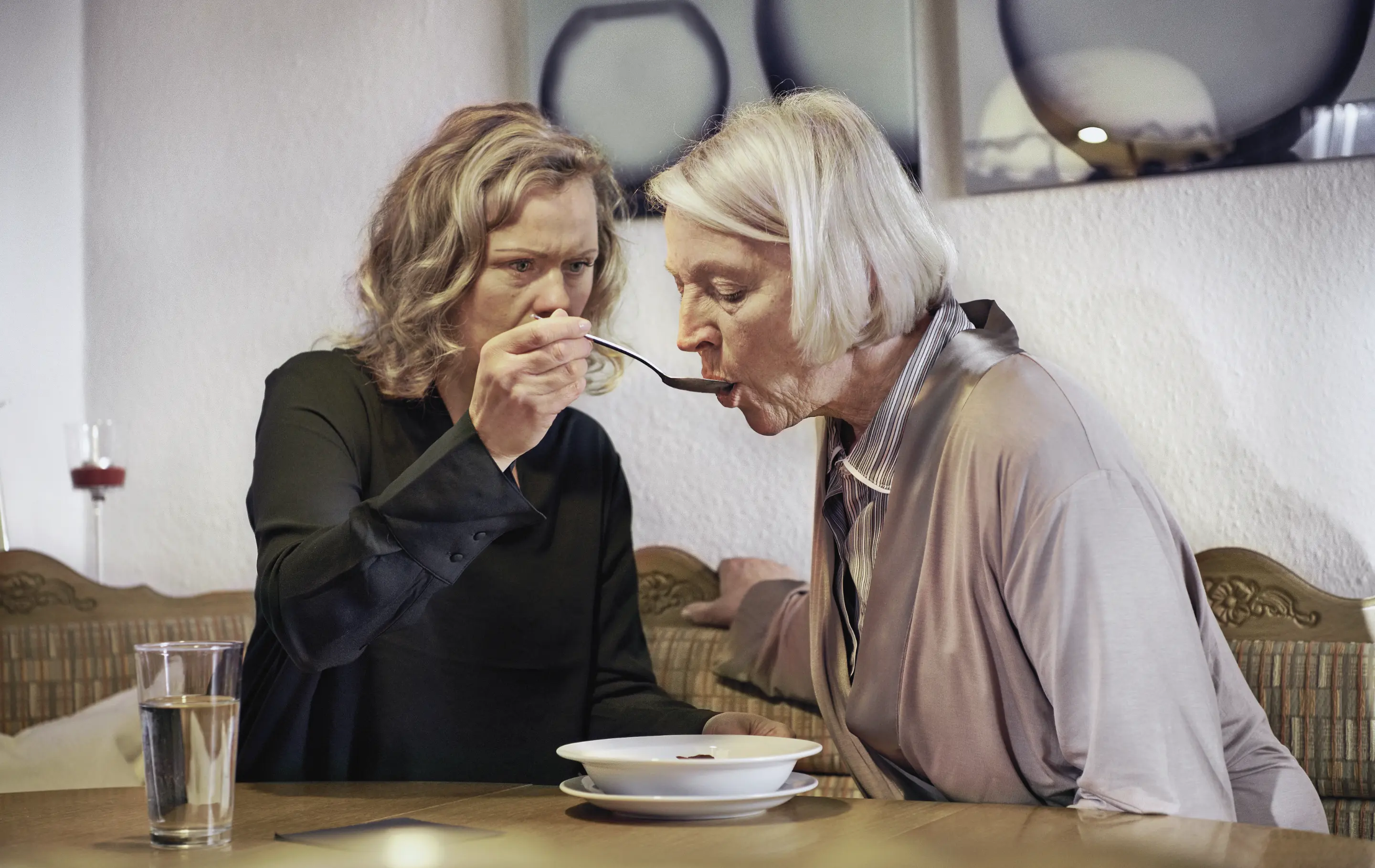 Eine jüngere Frau unterstützt eine ältere Frau beim Essen.