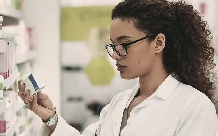 Apothekerin liest Medikamentenverpackung