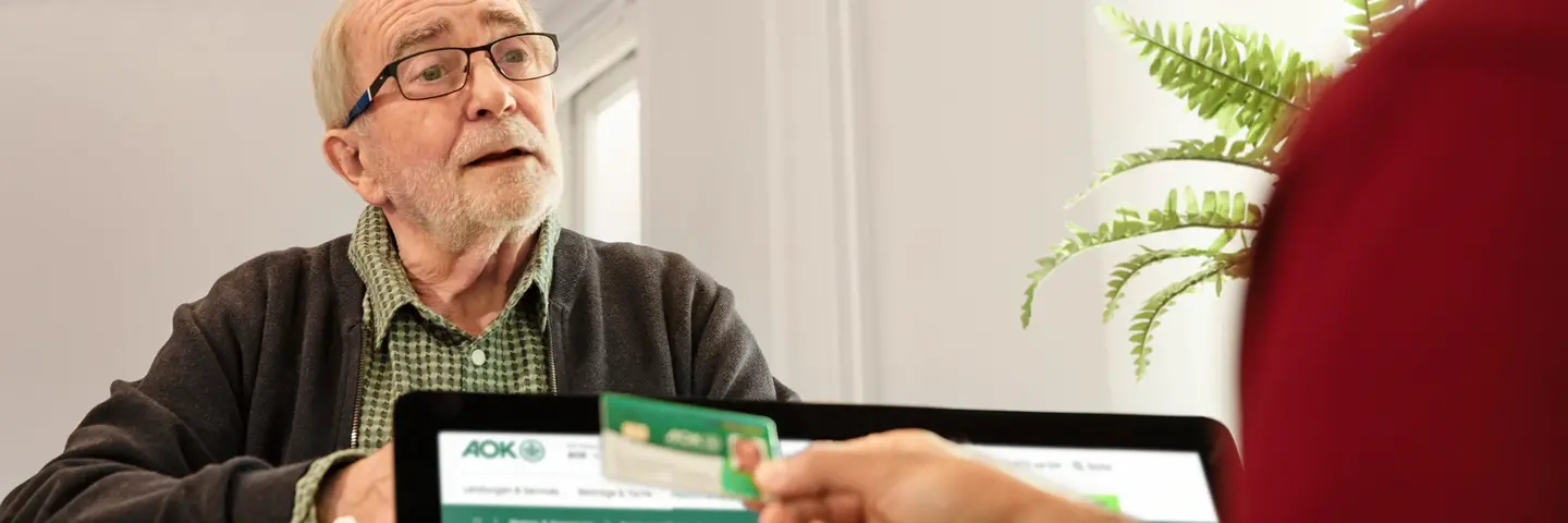 Patient meldet sich in Arztpraxis an und zeigt seine Gesundheitskarte. Patient meldet sich in Arztpraxis an und zeigt seine Gesundheitskarte.