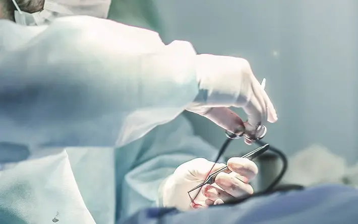 Chirurg hält OP-Besteck in den Händen und operiert Patienten