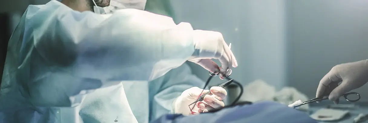 Chirurgie Foto: Chirurg hält OP-Besteck über einen OP-Bereich