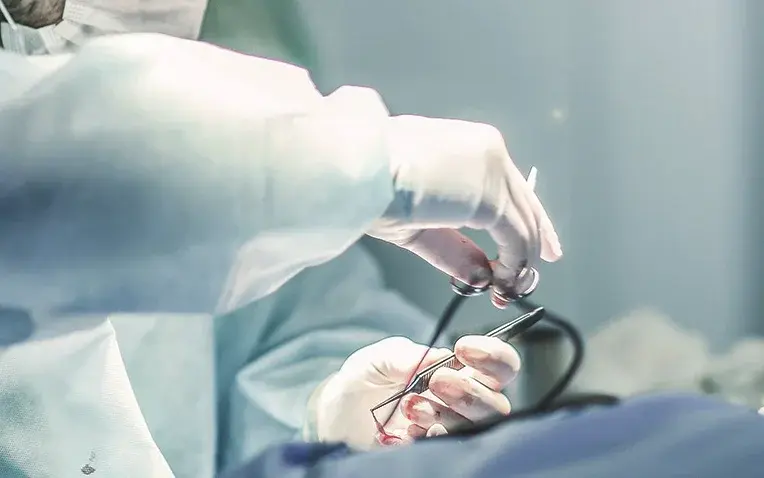 Foto: Chirurg hält OP-Besteck über einen OP-Bereich