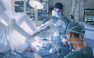 Chirurgieteam arbeitet im Operationssaal mit einem robotergestützten OP-System.