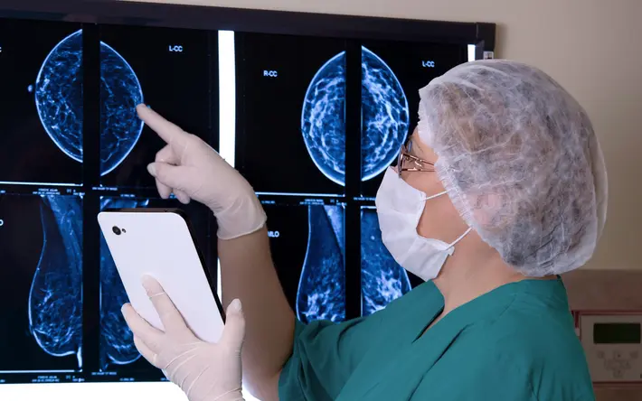 Arzt mit Tablet in der Hand prüft Mammografie-Aufnahmen. 