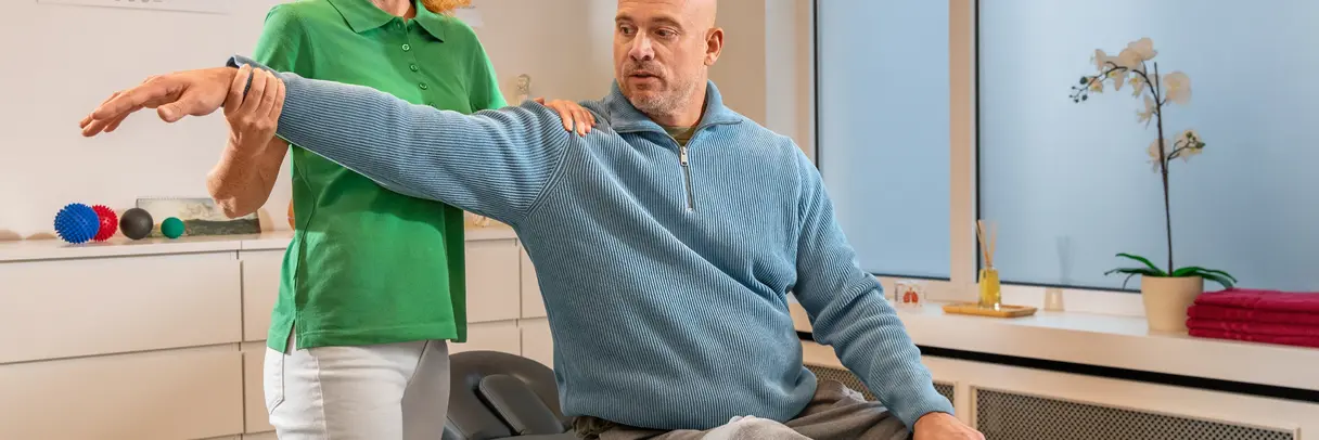 Eine Physiotherapeutin behandelt einen Patienten auf einer Physiotherapieliege.