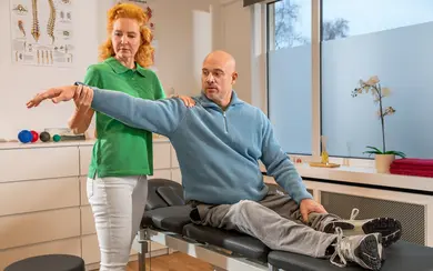 Eine Physiotherapeutin behandelt einen Patienten auf einer Physiotherapieliege.