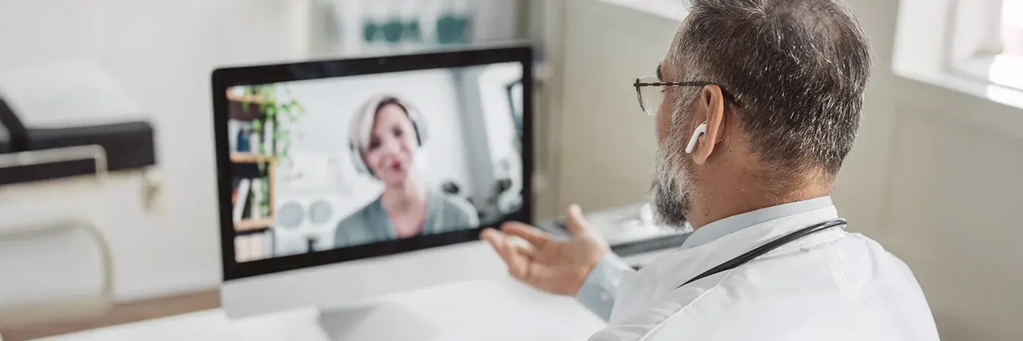 Das Bild zeigt einen Arzt im Videogespräch mit einer Patientin