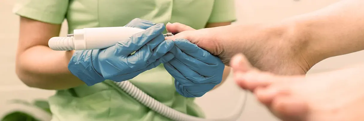 Podologin Fuß Podologin nimmt Fußpflege mit speziellen Geräten beim Patienten vor