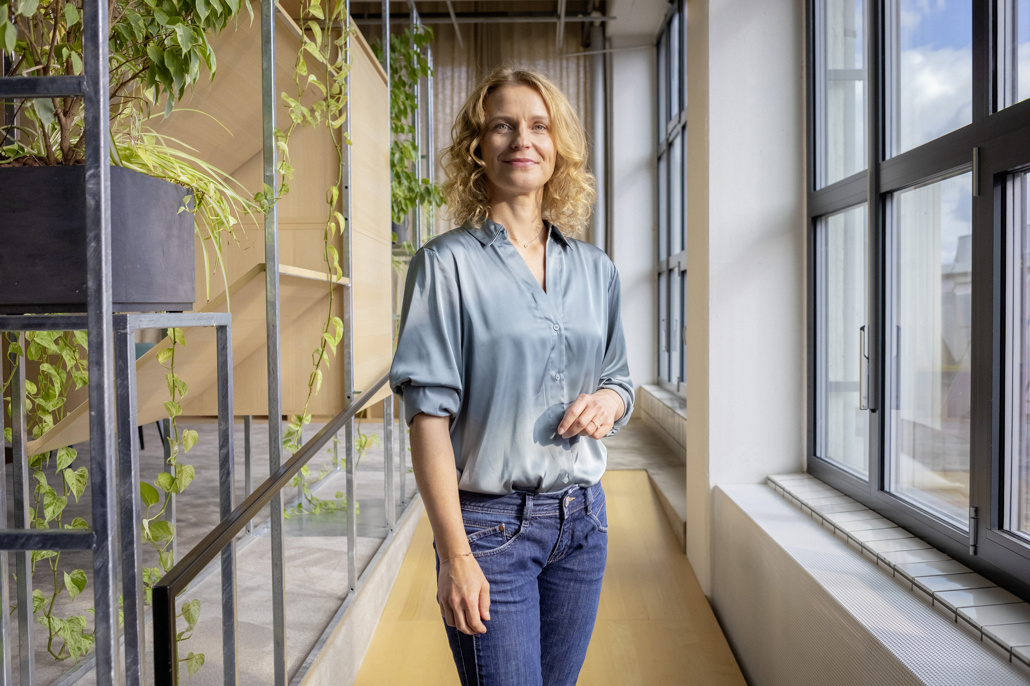 Eine berufserfahrene Frau steht im Flur ihres AOK-Büros.