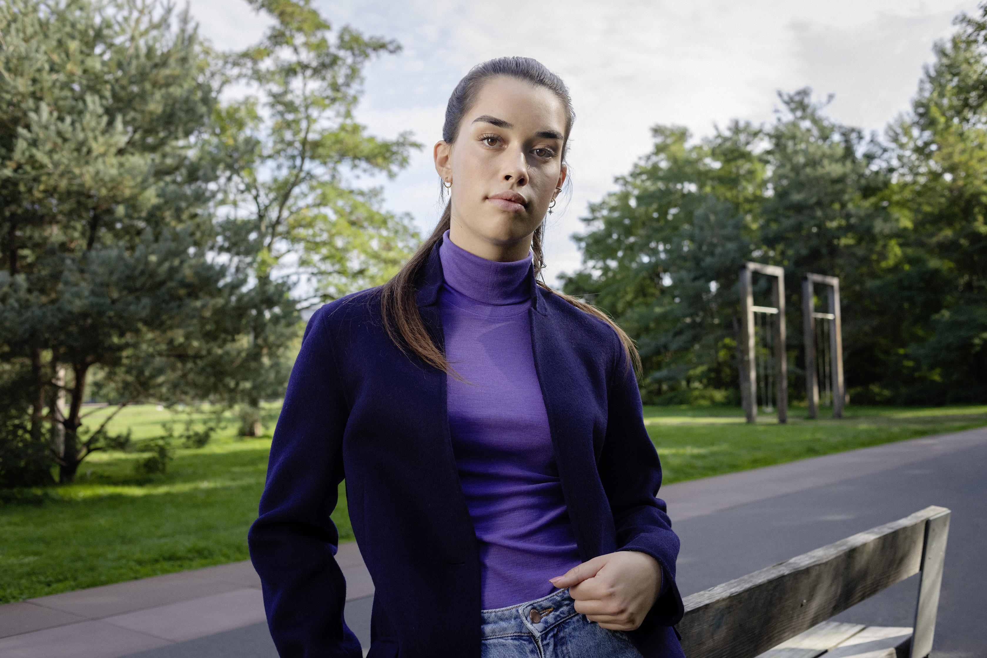 Eine Studentin lehnt an einer Parkbank.