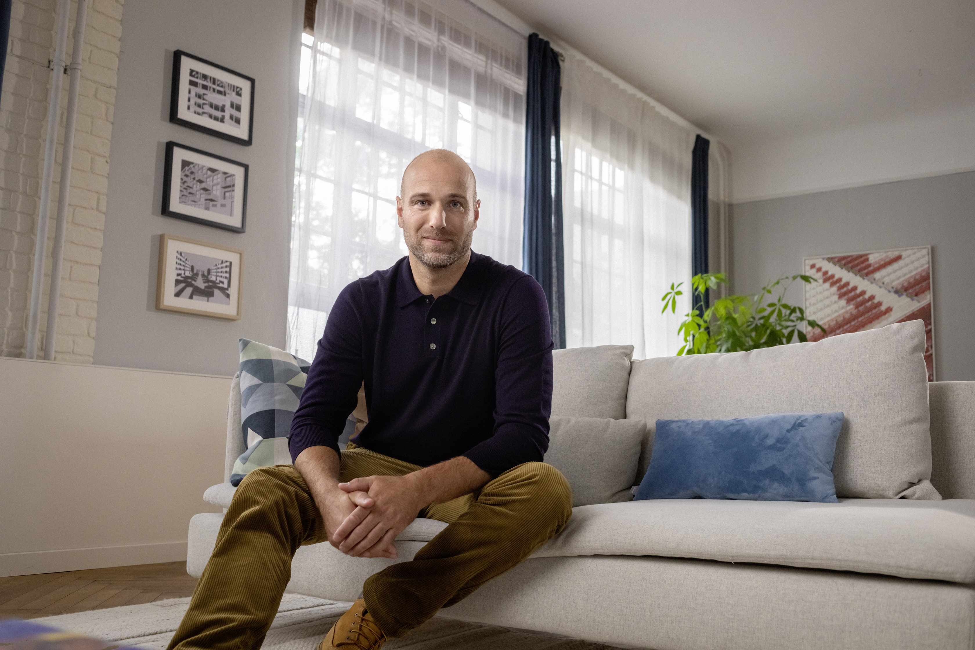 Ein berufserfahrener Mann sitzt auf der Couch in seinem Wohnzimmer.