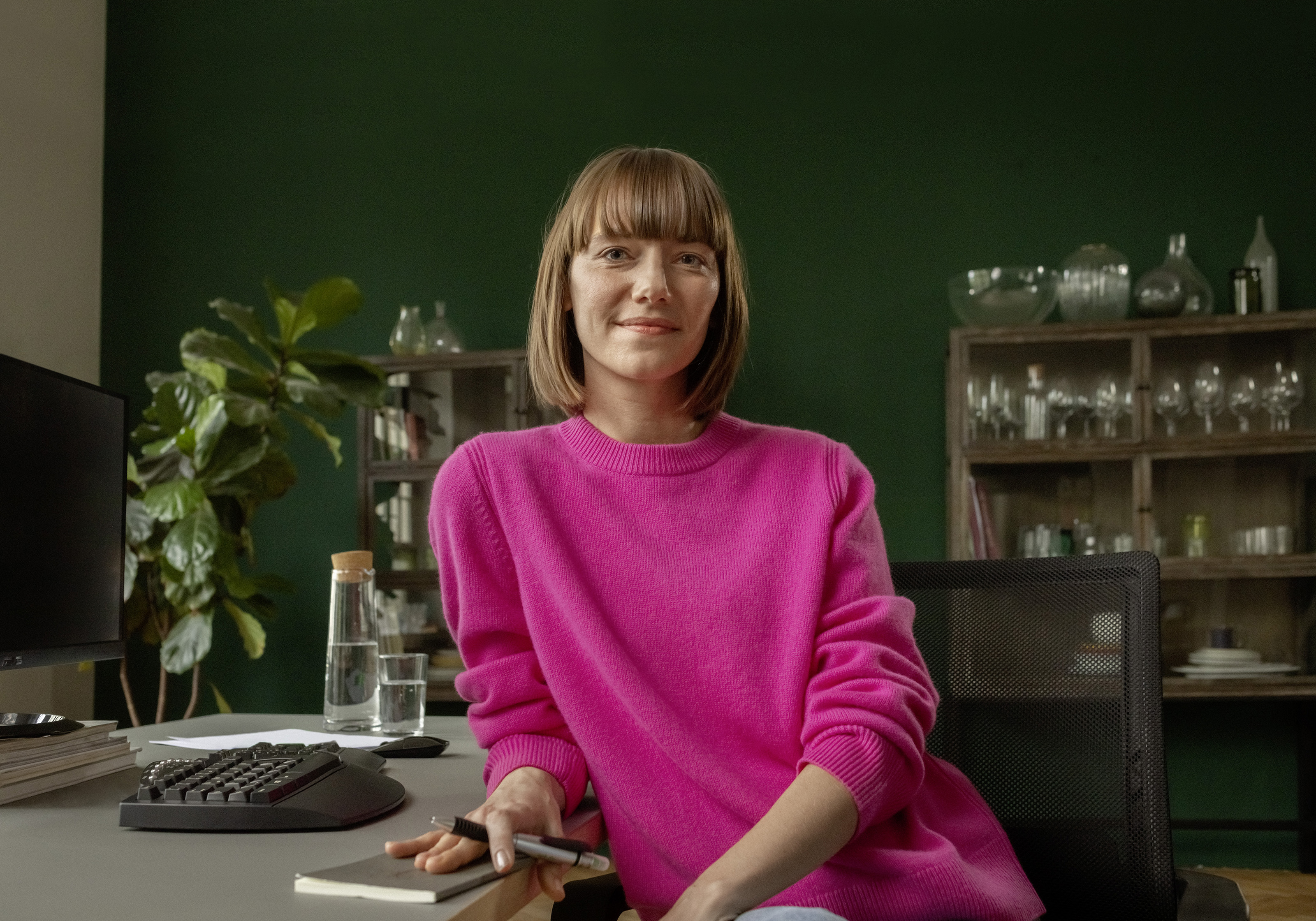 Eine berufserfahrene Frau lehnt an ihrem Schreibtisch im Homeoffice.