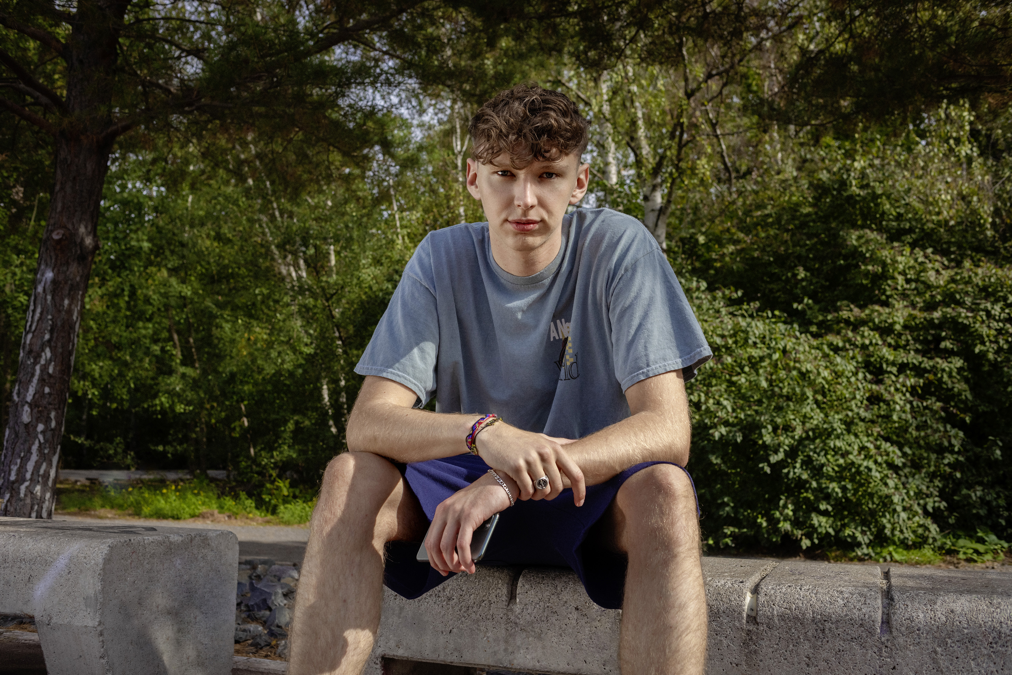 Ein Schüler sitzt im Park auf einer Mauer.