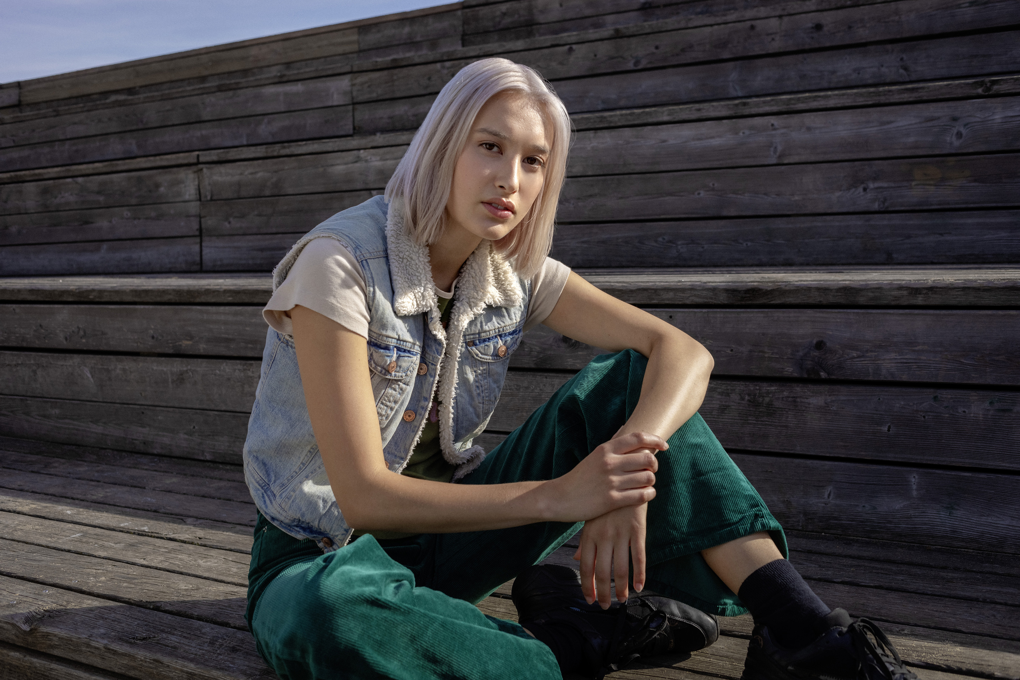 Eine Schülerin sitzt lässig auf einer Holzbank.