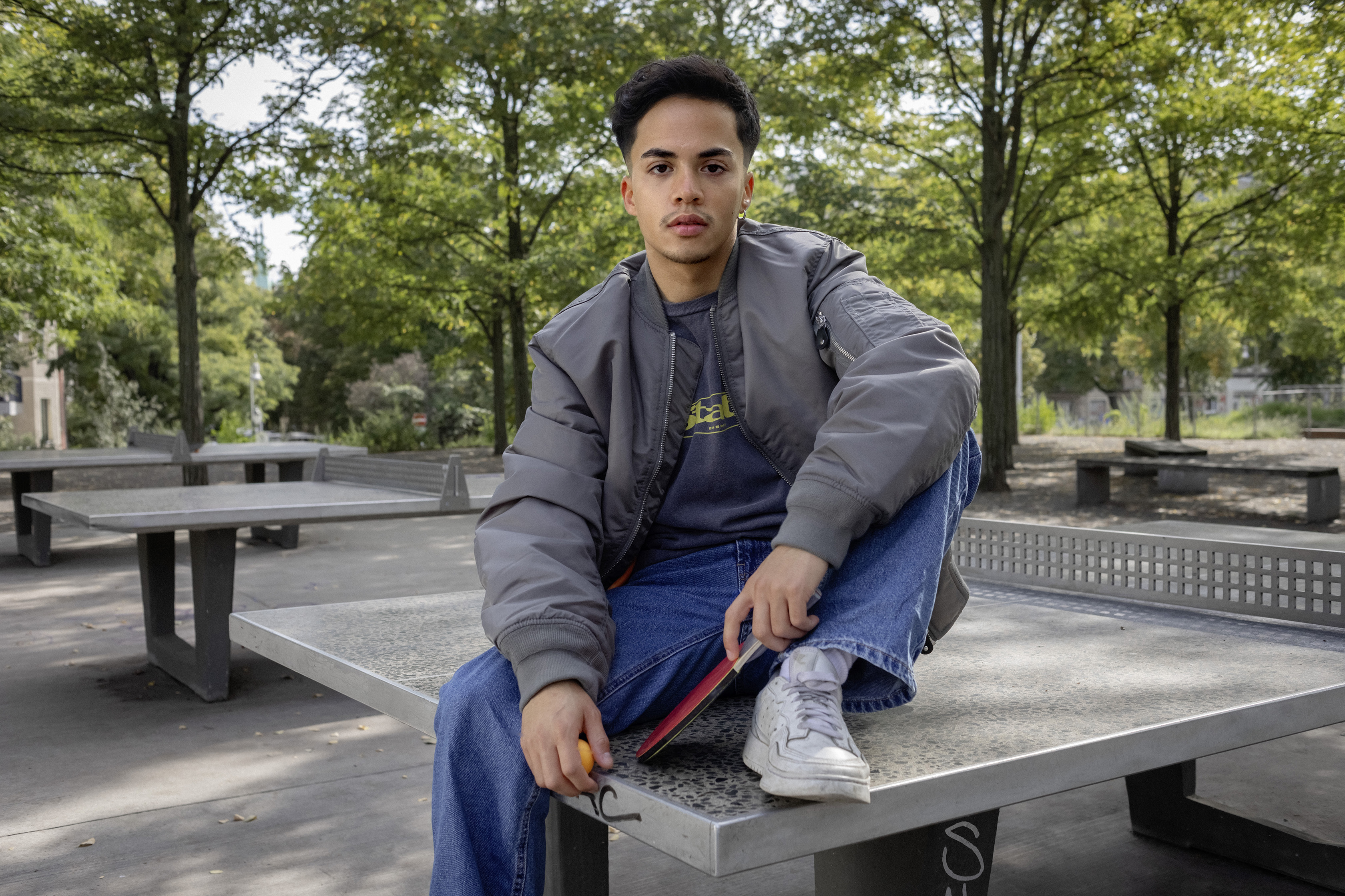Ein Schüler sitzt im Park auf einer Tischtennisplatte.