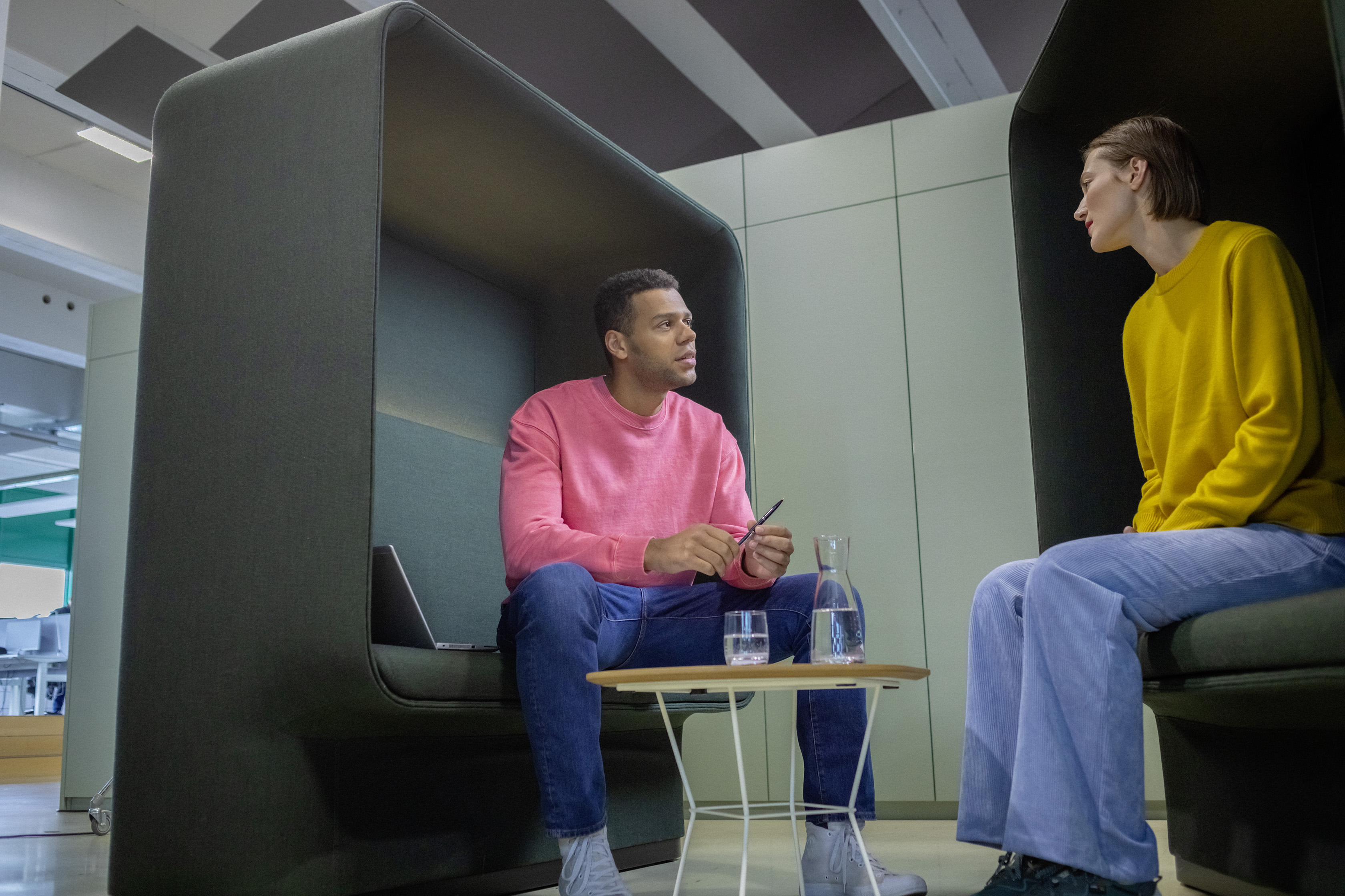 Ein berufserfahrener Kollege und seine Kollegin sitzen in einem Besprechungsraum und unterhalten sich.