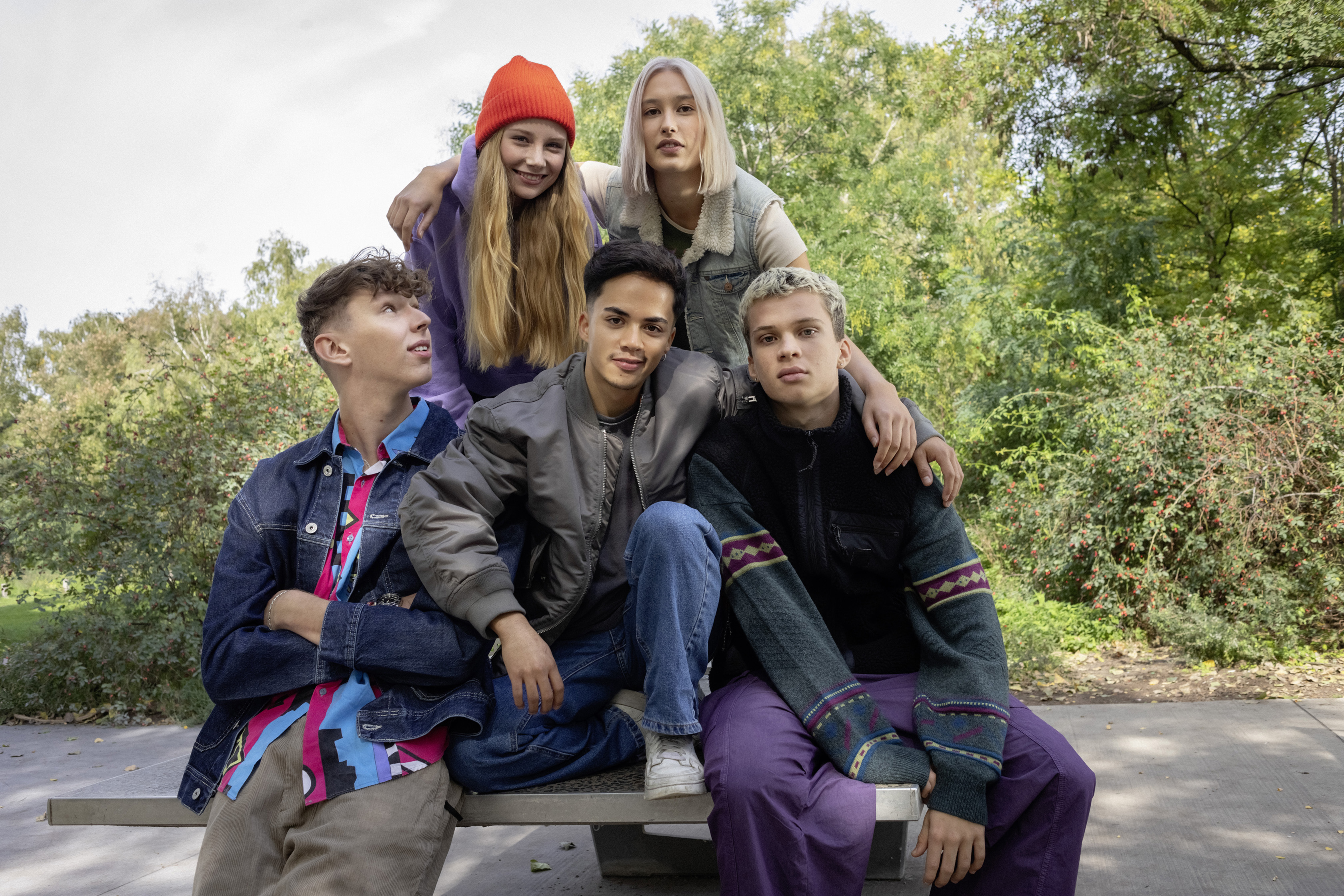 Eine Clique von Schülerinnen und Schülern posiert im Park für ein Foto.