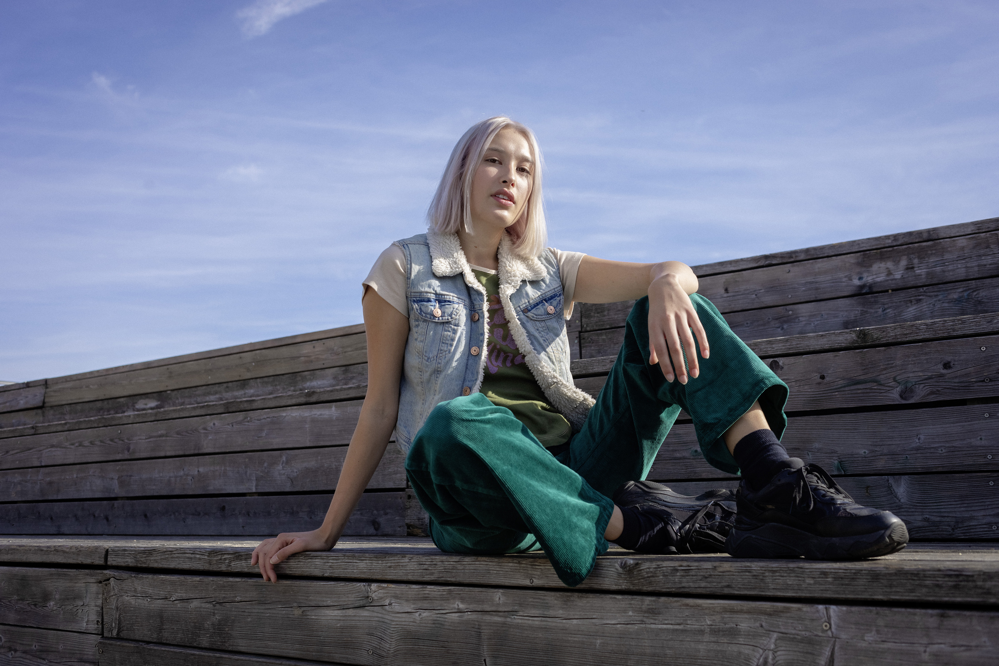 Eine Schülerin sitzt auf Holzstufen.