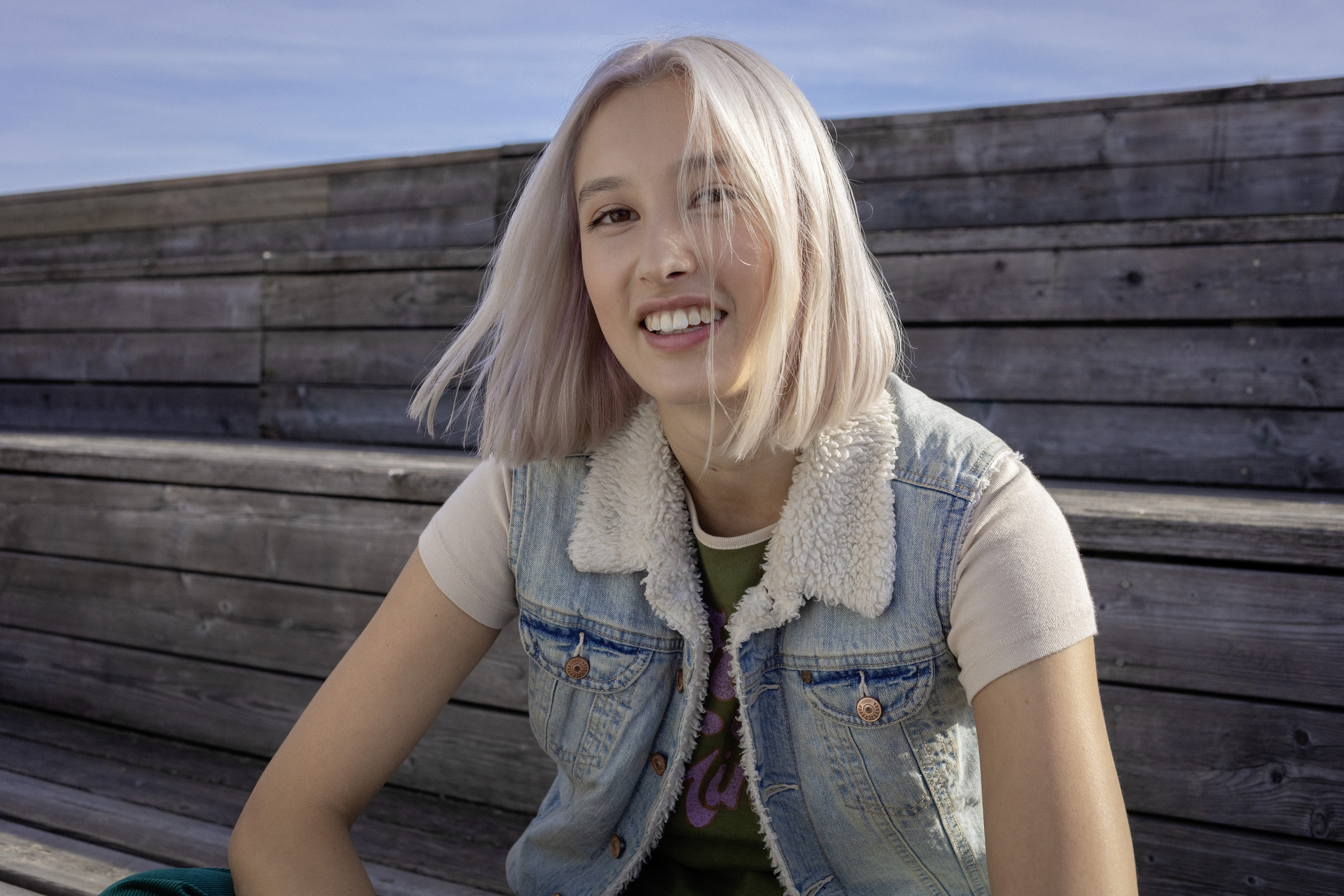 Eine Schülerin sitzt auf Holzstufen.