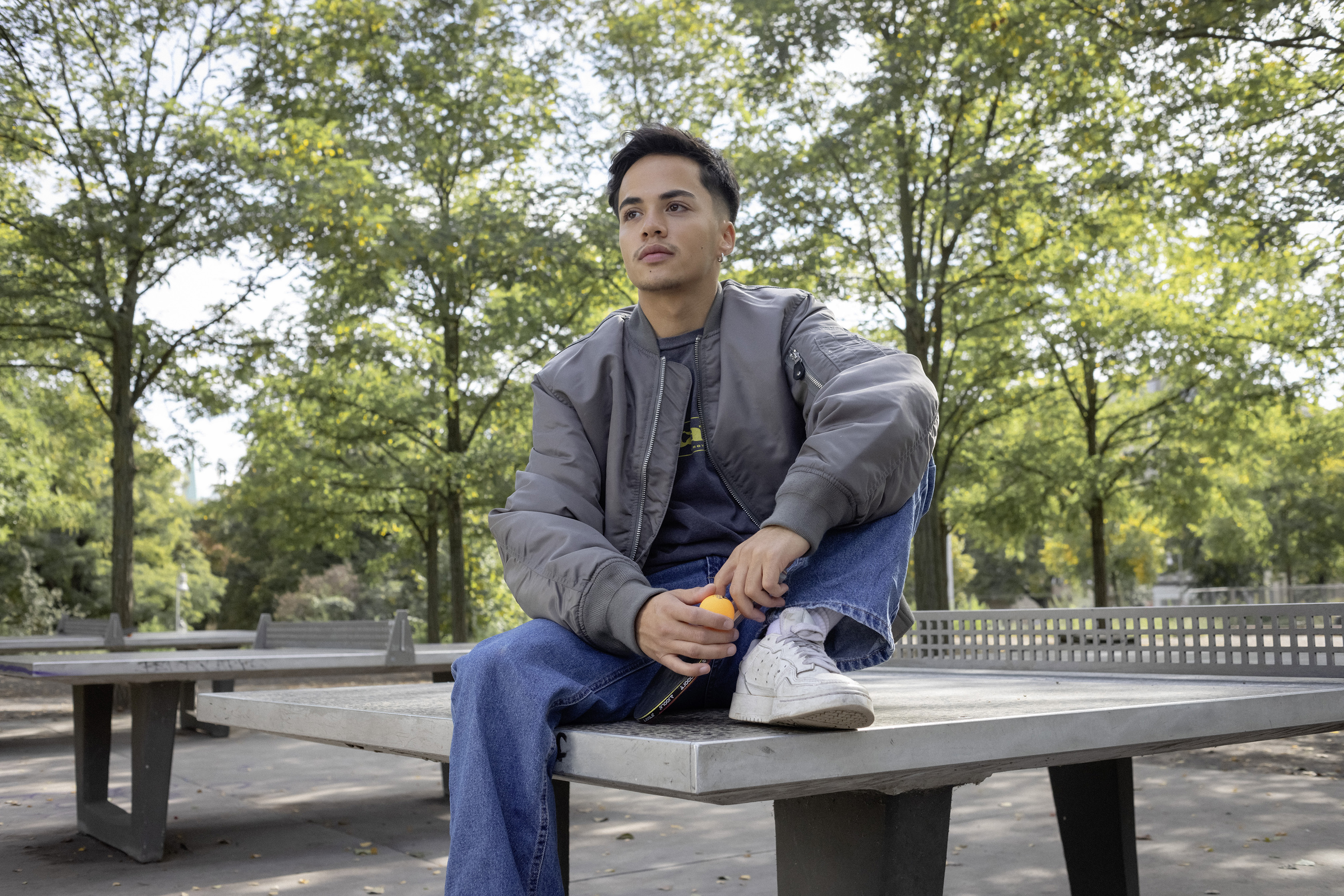 Ein Schüler sitzt im Park auf einer Tischtennisplatte.
