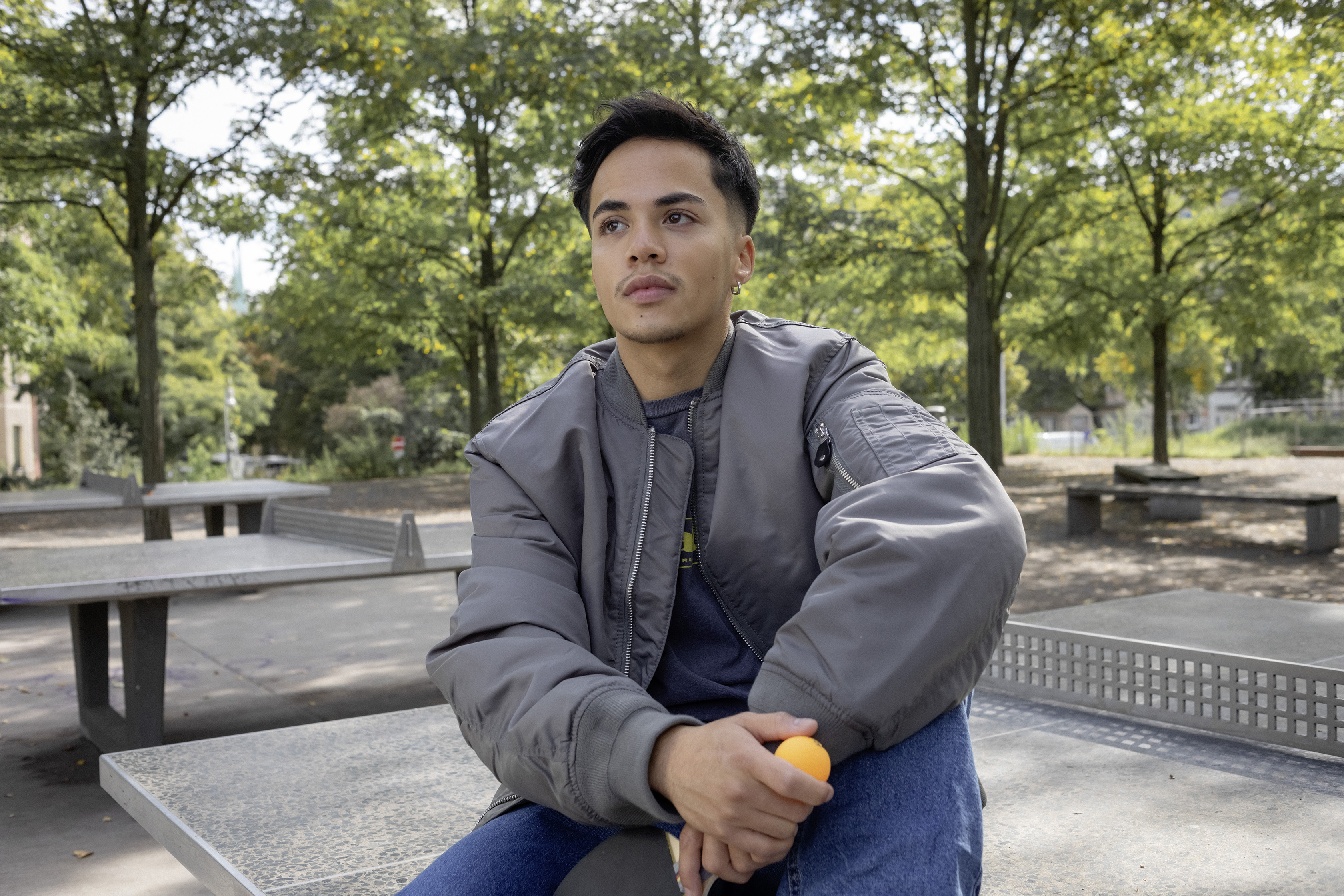 Ein Schüler sitzt im Park auf einer Tischtennisplatte.