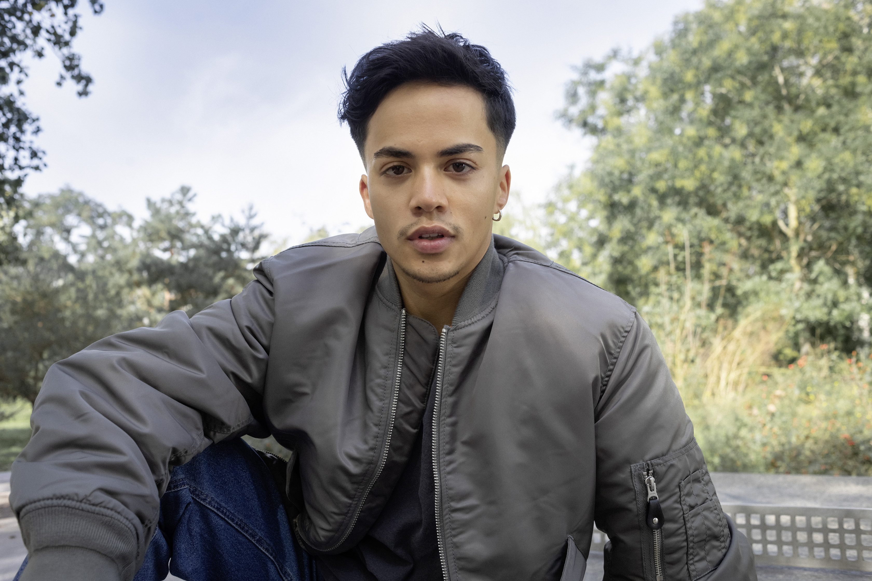 Ein Schüler sitzt im Park auf einer Tischtennisplatte.