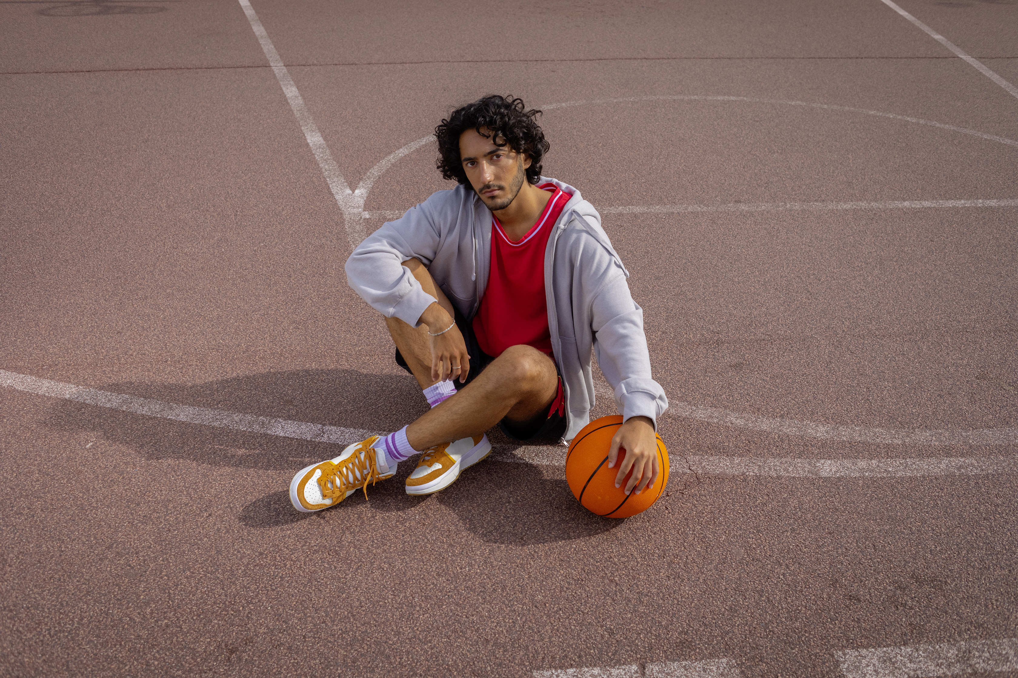 Ein Student sitzt auf einem Basketballfeld.