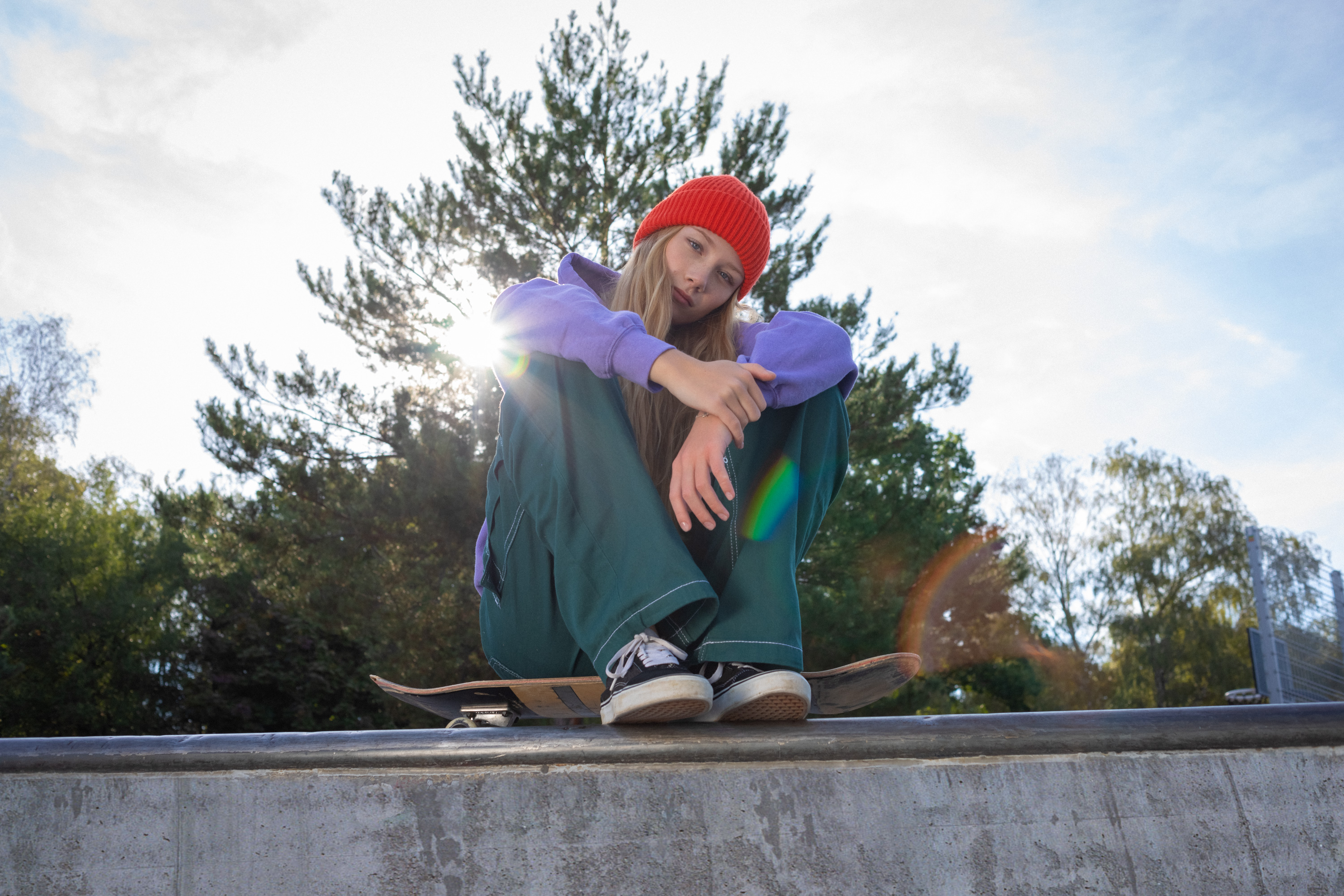 Eine Schülerin sitzt mit Skateboard im Skatepark.