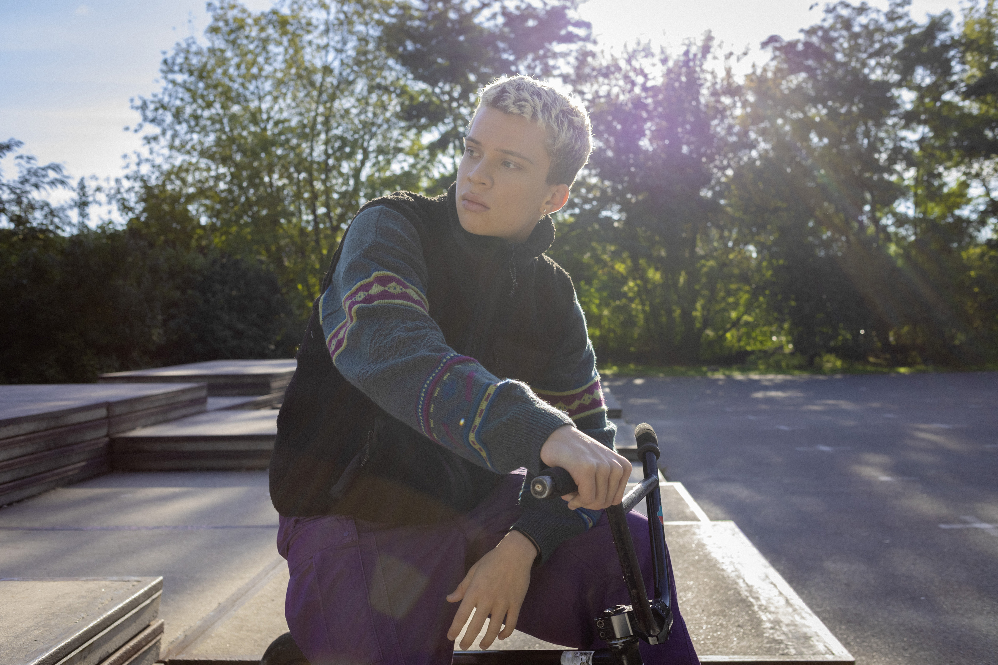 Ein Schüler lehnt im Park an seinem Fahrrad.