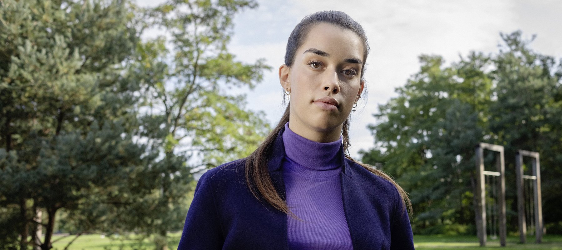 Eine Studentin lehnt an einer Parkbank.