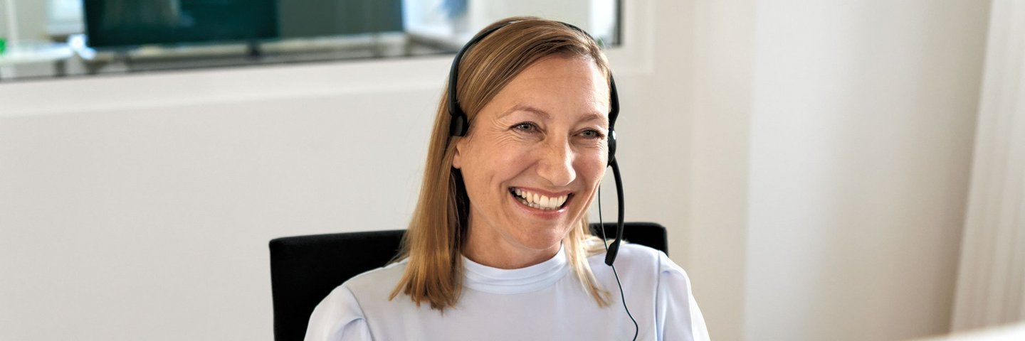 Eine AOK-Mitarbeiterin mit Headset nimmt Anrufe entgegen.