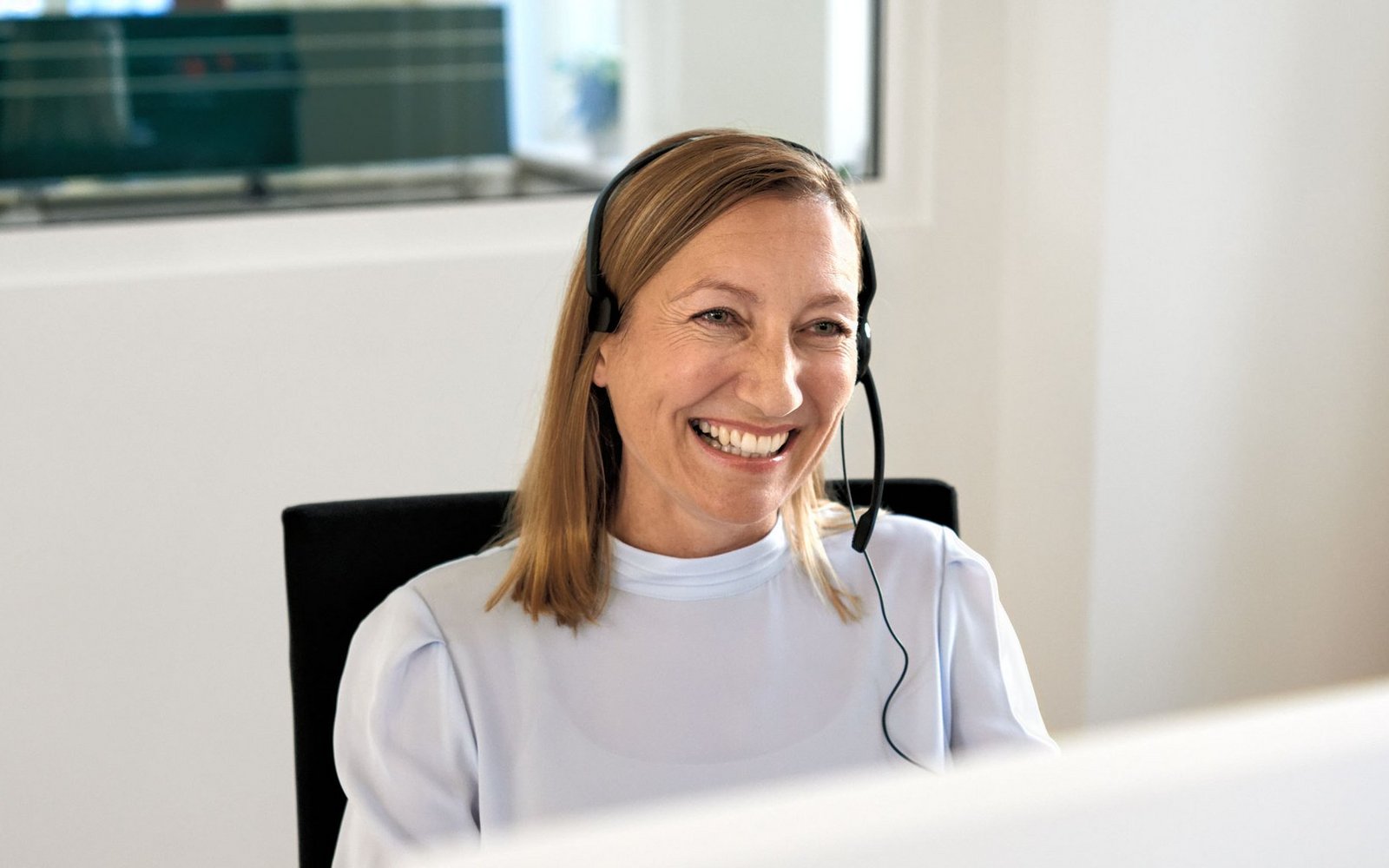 Eine AOK-Mitarbeiterin mit Headset nimmt Anrufe entgegen.