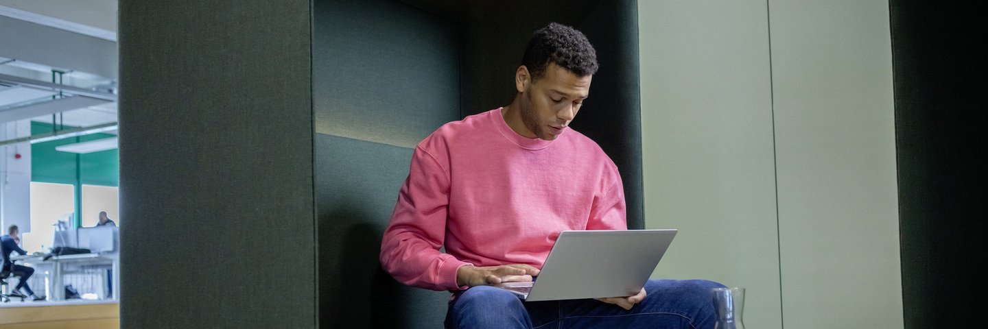 Ein berufserfahrener Mann sitzt mit Laptop in einem Besprechungsraum.