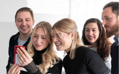 Das Team des AOK Campus schaut gemeinsam auf ein Handy.