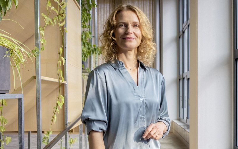 Eine berufserfahrene Frau steht im Flur ihres AOK-Büros.