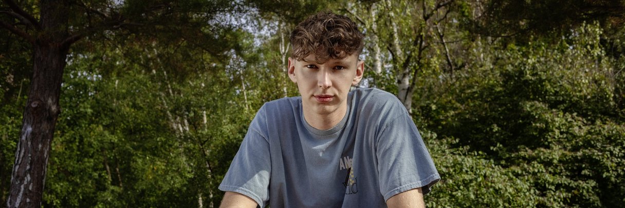 Ein Schüler sitzt im Park auf einer Mauer.