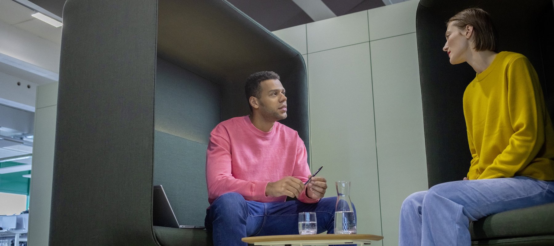 Ein berufserfahrener Kollege und seine Kollegin sitzen in einem Besprechungsraum und unterhalten sich.