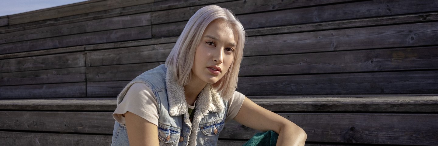 Eine Schülerin sitzt lässig auf einer Holzbank.