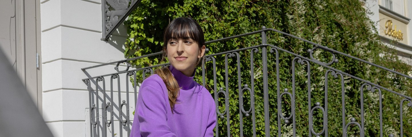 Eine junge Berufserfahrene sitzt auf einer Treppe vor dem Hauseingang.