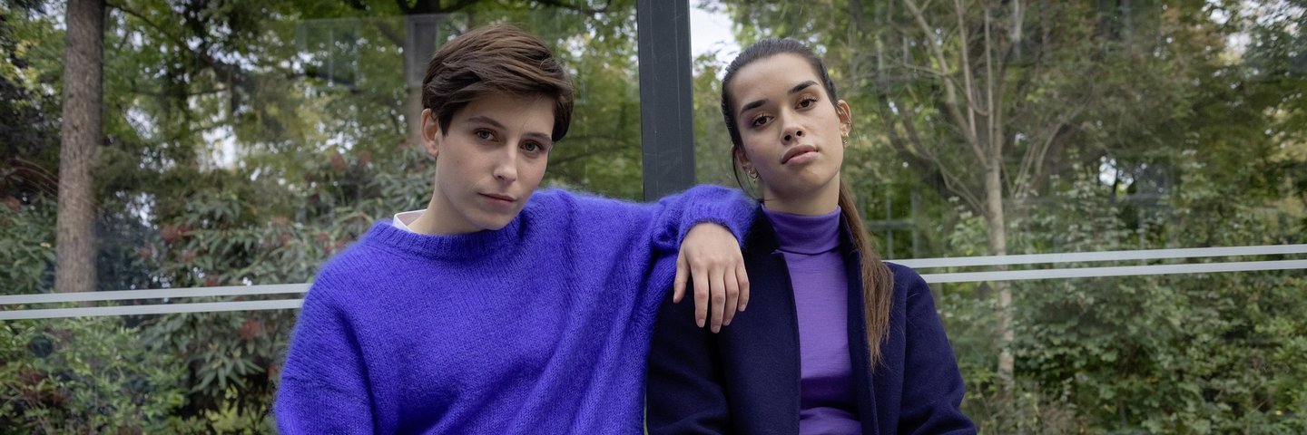 Zwei junge Frauen sitzen an einer Bushaltestelle